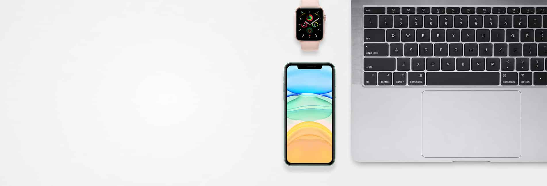 Top-down view of a laptop on the right with a green-edged iPhone centered below and a pink smartwatch above on a white surface.