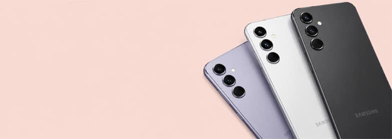 Three Samsung Galaxy smartphones in black, silver, and lavender finishes displayed on a soft peach background with ample space for promotional text.